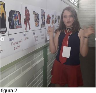 Bárbara Jordana desenhista, aluna de Artes Visuais do Professor Leandro Monteiro, apresentando seu trabalho sobre Mangás no Circuito de Ciências e Artes da Regional de Sobradinho. Ela está diante de um mural, vestida como um personagem de mangá.